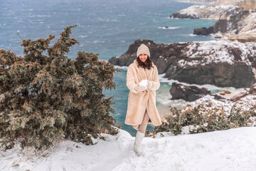 Woman snow sea. Amidst a wintry backdrop, a woman in a beige faux fur coat gleefully engages in a...