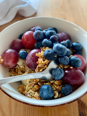Bluberries with granola and purple grapes in breakfast bowl.