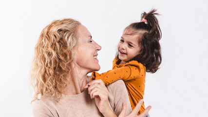 Mother and daughter looking at each other's smiling faces on white background