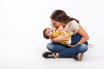 A mother holds her son playing with him on white background