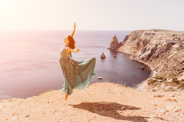 Woman green dress sea. Female dancer posing on a rocky outcrop high above the sea. Girl on the...