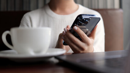 Business woman working online in a modern coffee shop with a smartphone in her hands and a laptop. Concept of freelancing, business, negotiations and remote work.