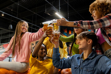 group of multiracial young people at the bar toasting with beers