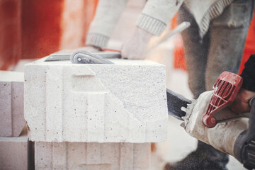 Workers cutting autoclaved aerated concrete block with chainsaw closeup. Builders cutting white...