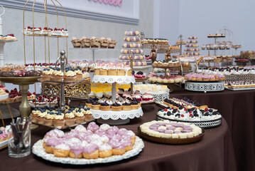 a table topped with lots of different types of cakes and pastries on trays 