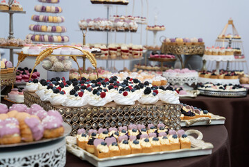 a table topped with lots of different types of cakes and pastries on trays 