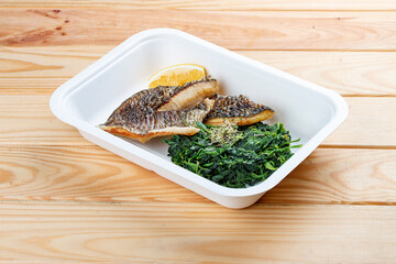 Sea bass fillet with spinach. Healthy food. Takeaway food. On a wooden background.