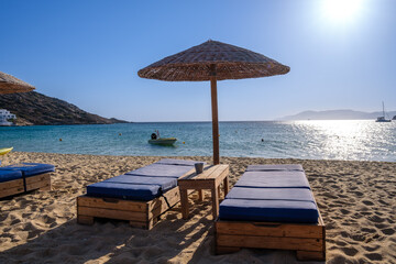 View of  sunbeds and a sun umbrella at the amazing beach of Mylopotas  in Ios Greece