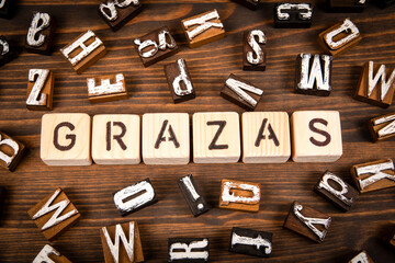 Thank you in Galician. Alphabet blocks on wood texture background