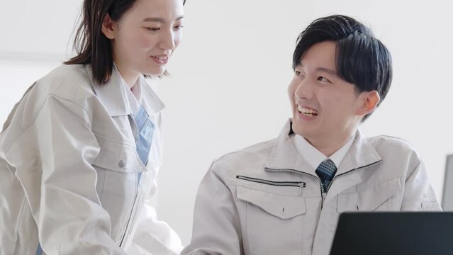 パソコンを見る作業着を着たビジネスマンたち
