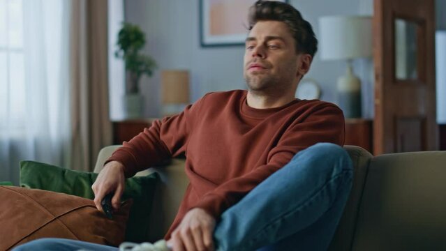Tired man choosing channel relaxing home sofa after hard day close up. Bored guy