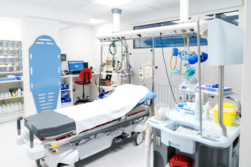 Clean, organized ER room with medical machinery and patient bed.