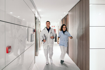 Two healthcare professionals, a doctor and a nurse, swiftly moving through the brightly lit...