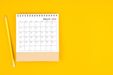 March 2024 desk calendar and wooden pencil on yellow color background.