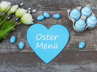 Fototapeta na wymiar Ostermenü auf ein Herz geschrieben mit Blumen und Ostereiern dekoriert.