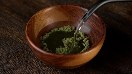 Preparing for drink matcha green tea. Pouring water in matcha powder 