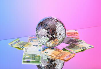 Mirror disco ball, lots of money. Currency and savings concept.