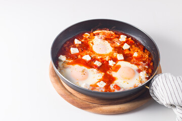 Shakshuka made of poached eggs in tomato pepper sauce