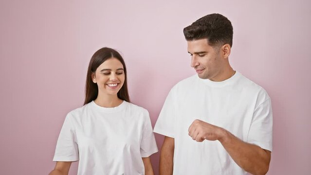 A man and woman in white shirts fist bumping against a pink background, depicting a casual, friendly relationship.