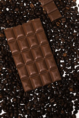 chocolate lies on coffee beans. Chocolate is layered on top of the coffee beans, creating contrasting textures and colors. composition with coffee beans and chocolate, background