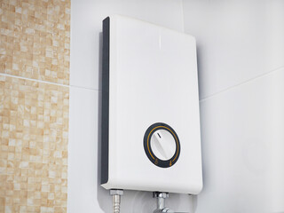 Modern electric water heater on the tile wall in the bathroom.