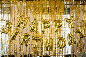Birthday party. Happy birthday, text. Arch decorated with golden balloons. Photo-wall decoration with gold background. Trendy autumn decor. Celebration concept.