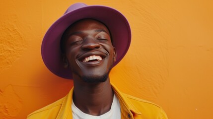 A joyful man with a big smile wearing a purple hat and a yellow jacket against an orange textured...