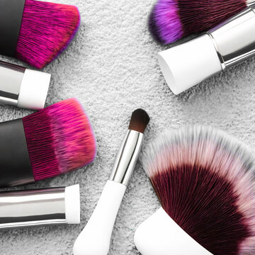 Top view of a set of colorful make up brushes on a textured surface