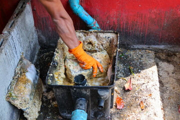 Grease traps from dirty debris being cleaned with a scoop are discarded. How to treat water with a...