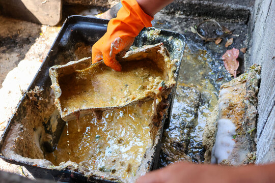 Grease traps from dirty debris being cleaned with a scoop are discarded. How to treat water with a grease trap.