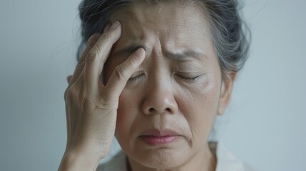 Fototapeta premium A woman with her hand on her forehead appearing to be in distress or deep thought.