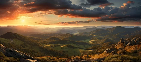 Fotobehang The painting depicts a vibrant sunset over the Czech Republics Orlicke hory mountain range. The sky is ablaze with hues of orange, pink, and purple, casting a warm glow over the rugged peaks. © AkuAku