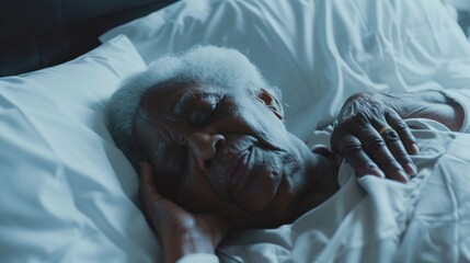 An elderly person with white hair peacefully sleeping on a bed with white sheets and pillows.