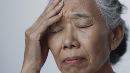 An elderly person with closed eyes resting their head on their hand showing signs of age and possibly fatigue or sadness.