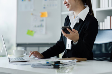 businesswomanman holding smartphone sitting in office. Manager using cell phone mobile app and laptop