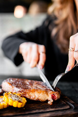 woman hands with fork and knife eating beef steak in cafe