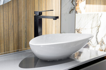 A sleek modern bathroom featuring a white vessel sink paired with a stylish black faucet, set...