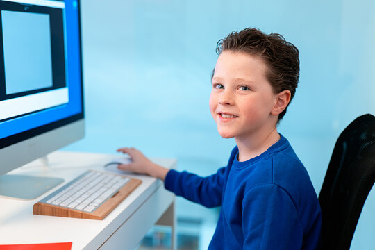 A smiling boy enjoys his time on the computer, possibly participating in a virtual class or exploring educational software