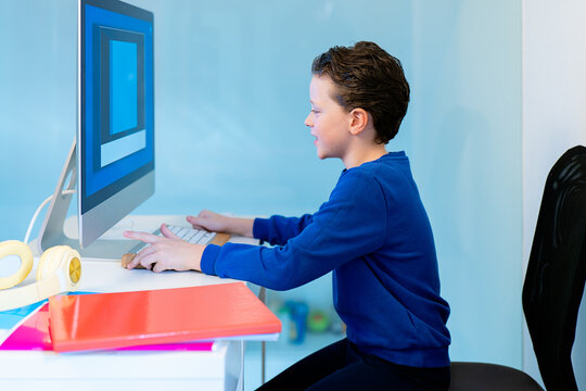 A focused young boy interacts with educational content on a desktop computer in a vibrant, colorful study space