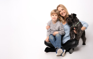 Fototapeta na wymiar Beautiful young mother with child boy and puppy schnauzer dog sitting on floor on white background