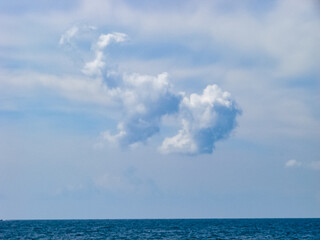 Magical seascape with a big fluffy cloud above the sea horizon. A cloud over the calm blue sea.