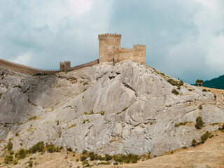 A medieval fortress on a stone rock against the background of a clear blue sky.