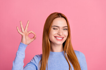 Portrait of good mood girl with foxy hairdo wear blue pullover winking eye show okey approve quality isolated on pink color background - obrazy, fototapety, plakaty