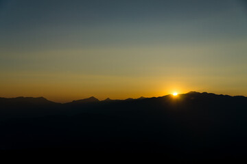The sun sets among the mountains.