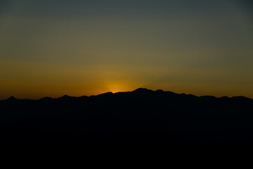 The sun sets among the mountains.