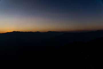 The sun sets among the mountains.