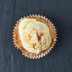 Beautiful inviting rustic gourmet Sponge and cream cup cakes with a shallow depth of field, photographed on a grey slate table. Sprinkles and sweet sugary crumble.