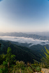 Misty mountain landscape, clear blue cloudless sky and layers of hills. Cold mood.
