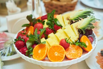 A plate of fruits on the festive table. Citrus fruits and berries.