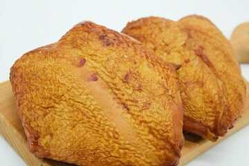 Meat dish smoked chicken breasts on a wooden board. The product is ready to use. White background.